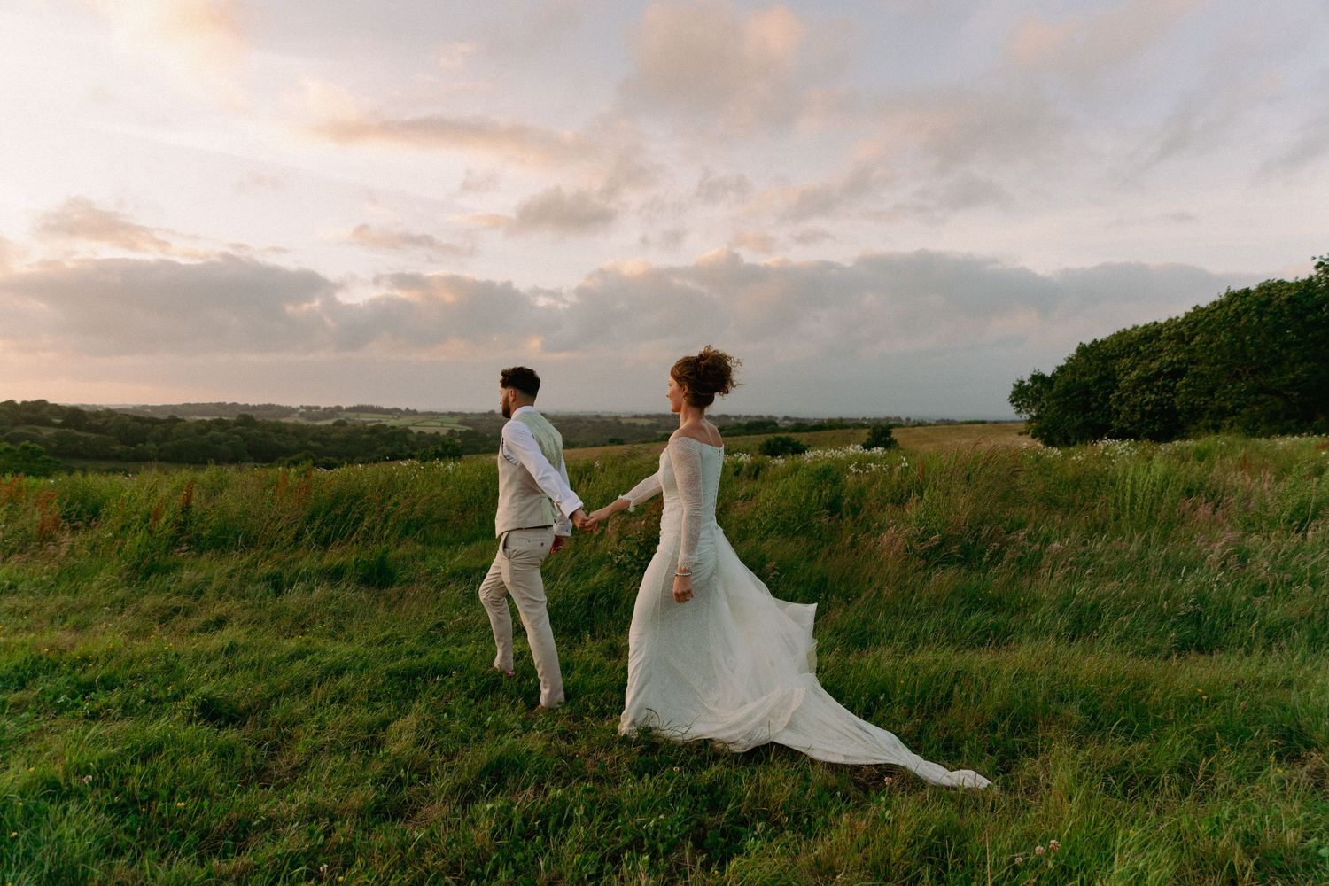 A couple in elegant white attire celebrating outdoors at night with sparkles falling in the background.