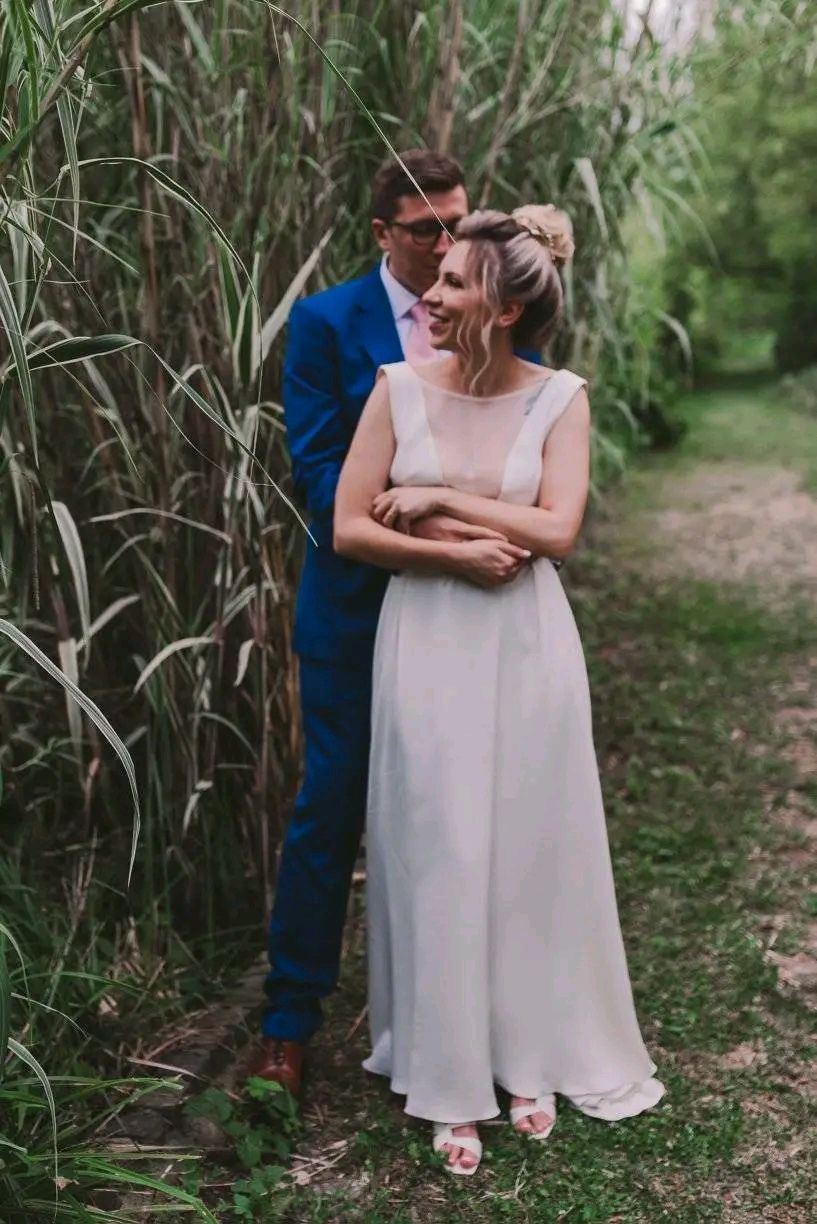 A couple shares a joyful moment together on a garden path surrounded by tall reeds and greenery.
