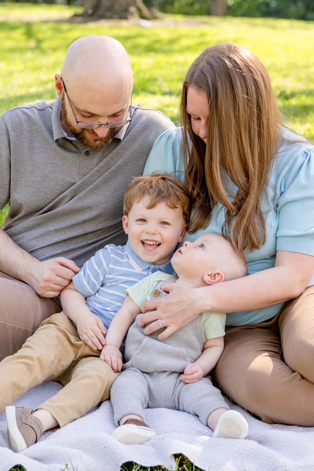 A family sits together on a blanket outdoors at Historic Oak View Park in Raleigh, NC!