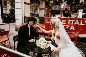 Bride and groom sharing a playful moment at a Little Italy pizza cafe on their wedding day.