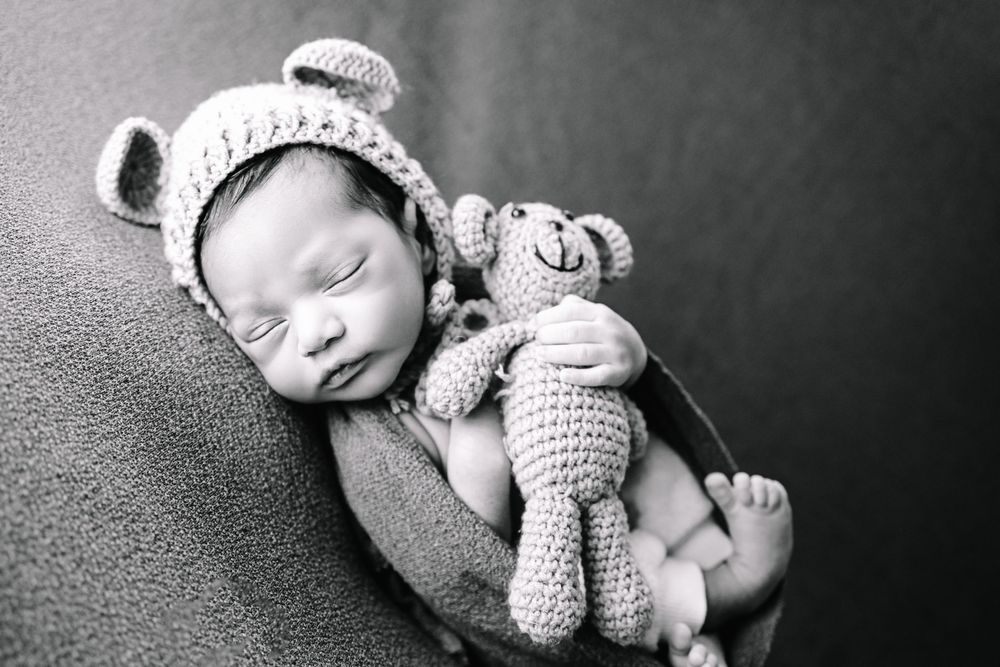 Newborn baby boy in Marietta GA on a green backdrop with a teddy bear