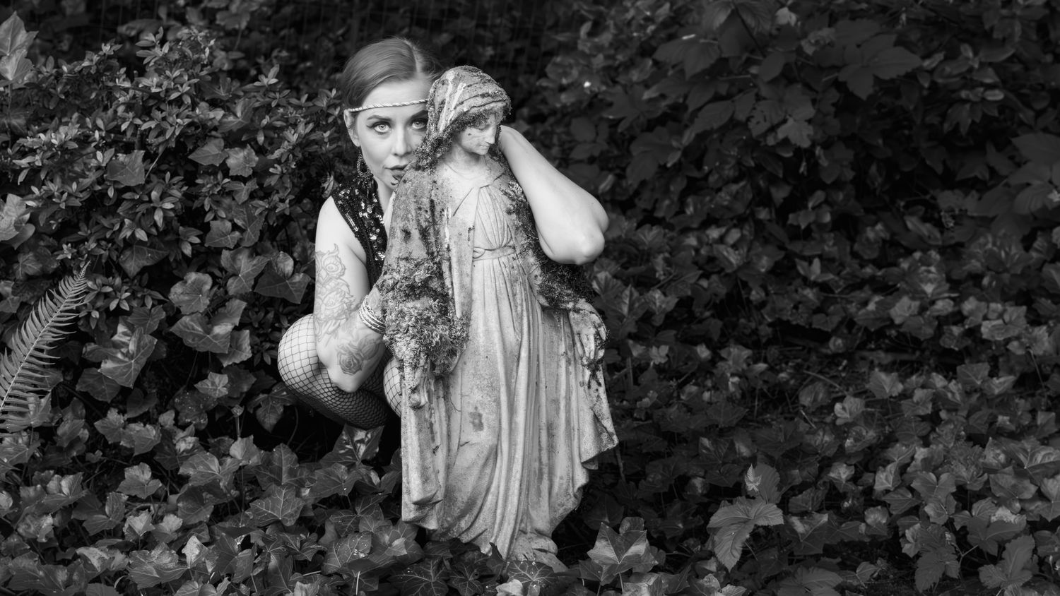 Black-and-white photo of bree, hiding behind a statue appearing to be possibly scared