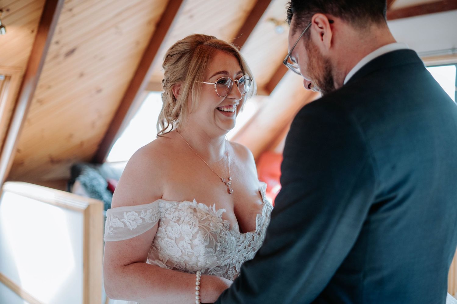 A joyful wedding interaction captured in a wood-paneled room with natural lighting.