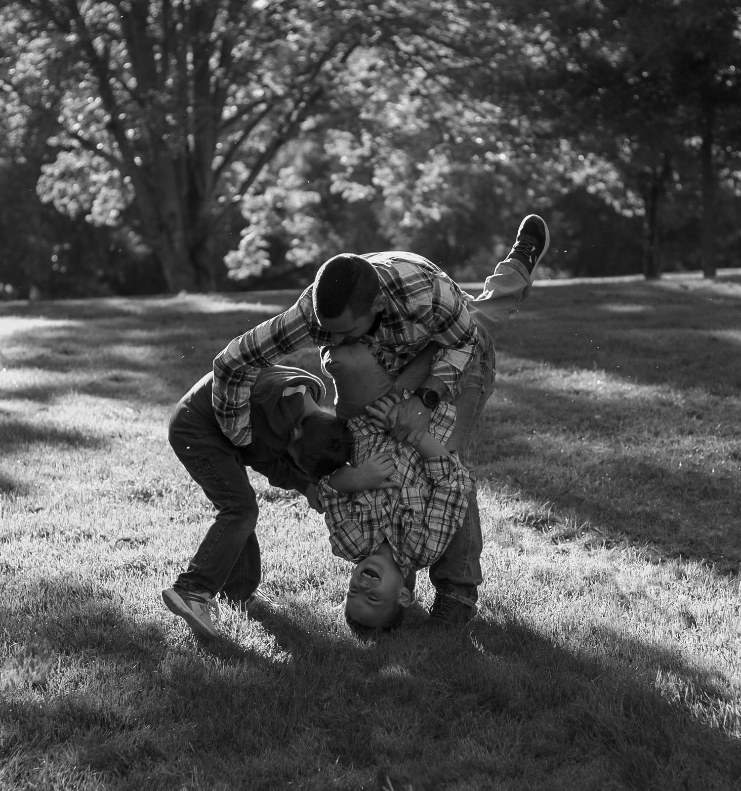 Black and white photo of two children playfully wrestling on a grassy lawn.