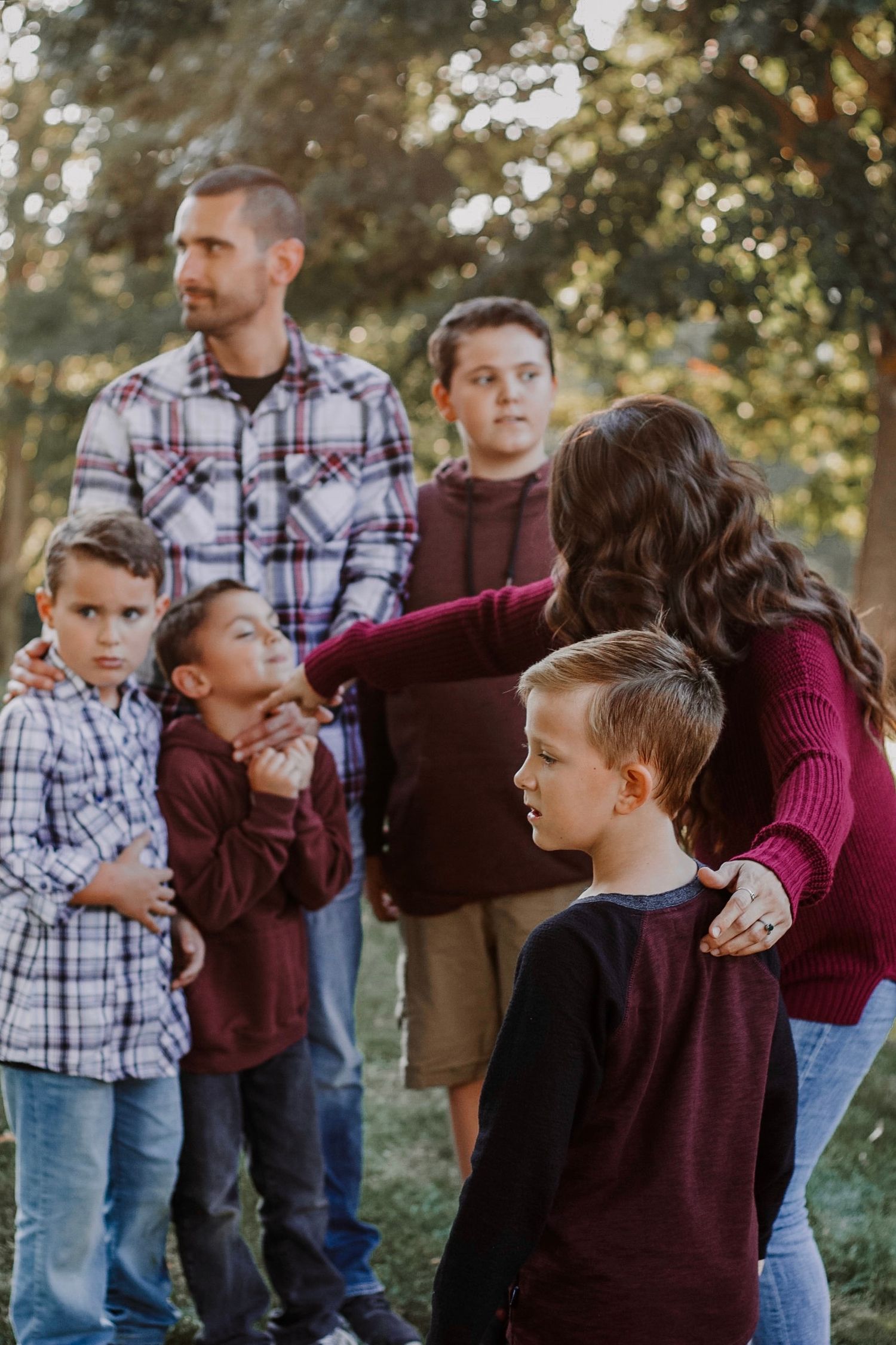 Candid family moment with parents and four boys in a sunlit autumn setting.