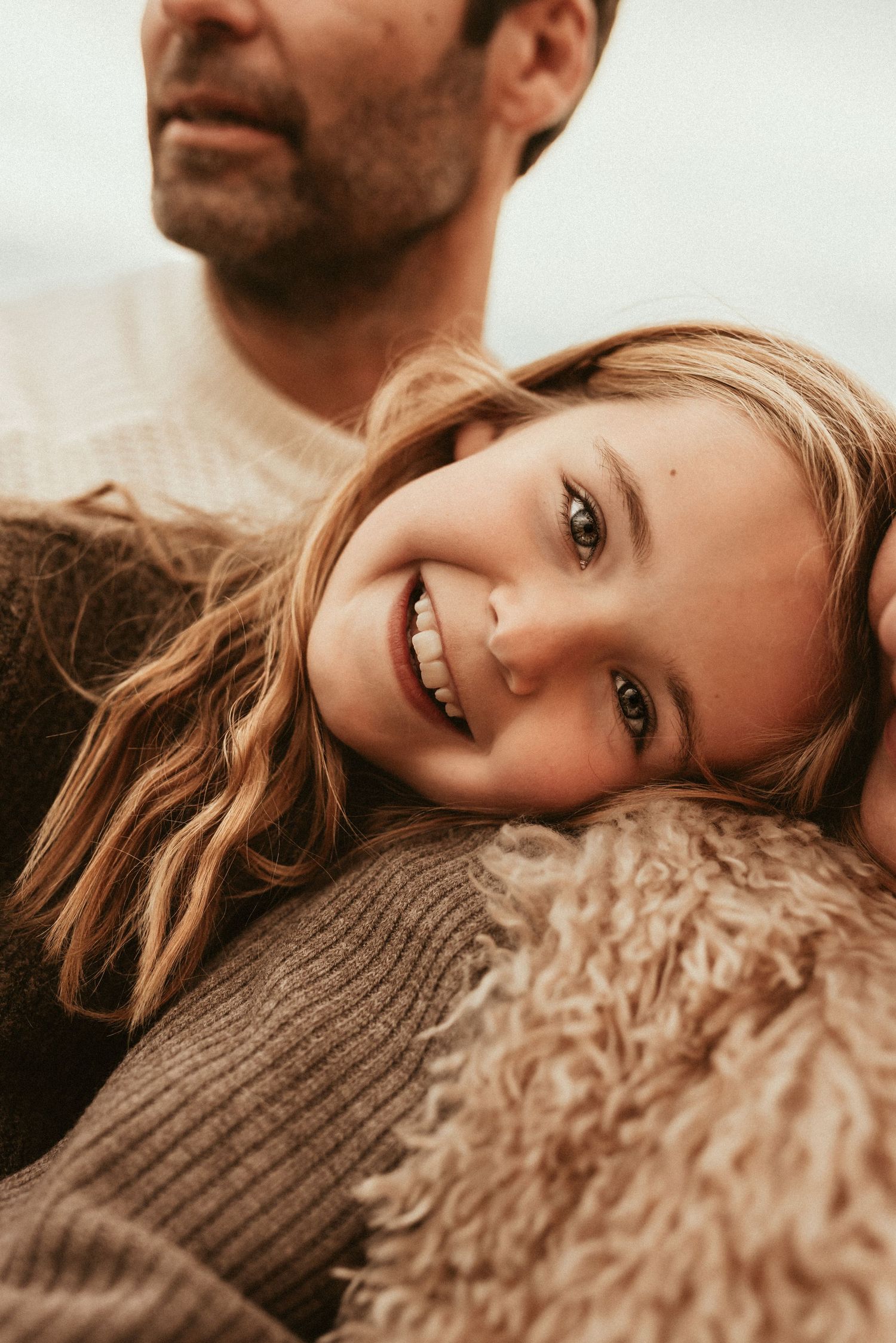 Close up warm toned portrait of someone with blonde hair and bright smile for family session with Denia Photographer