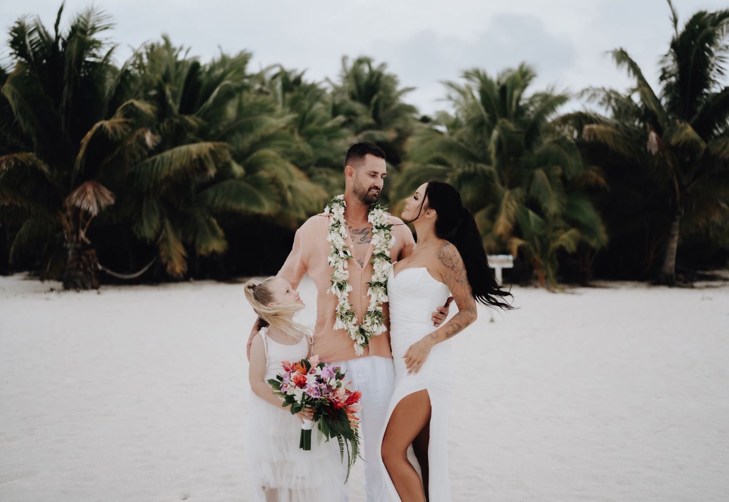 A romantic beach wedding ceremony with palm trees in the background as a couple celebrates on white tropical sand.