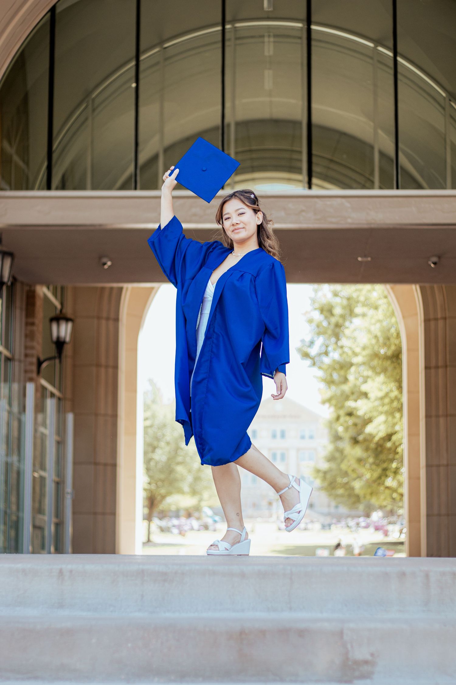 A person in a lilac fitted mini dress with cap sleeves poses confidently against a column in an outdoor walkway.