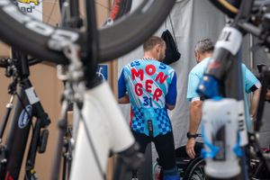 Cyclist wearing bright blue jersey with bikes in foreground and background at cycling event.