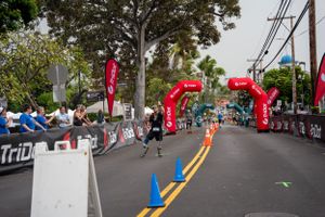Runners approach red inflatable arches at a road race finish line with spectators and cones marking the course.