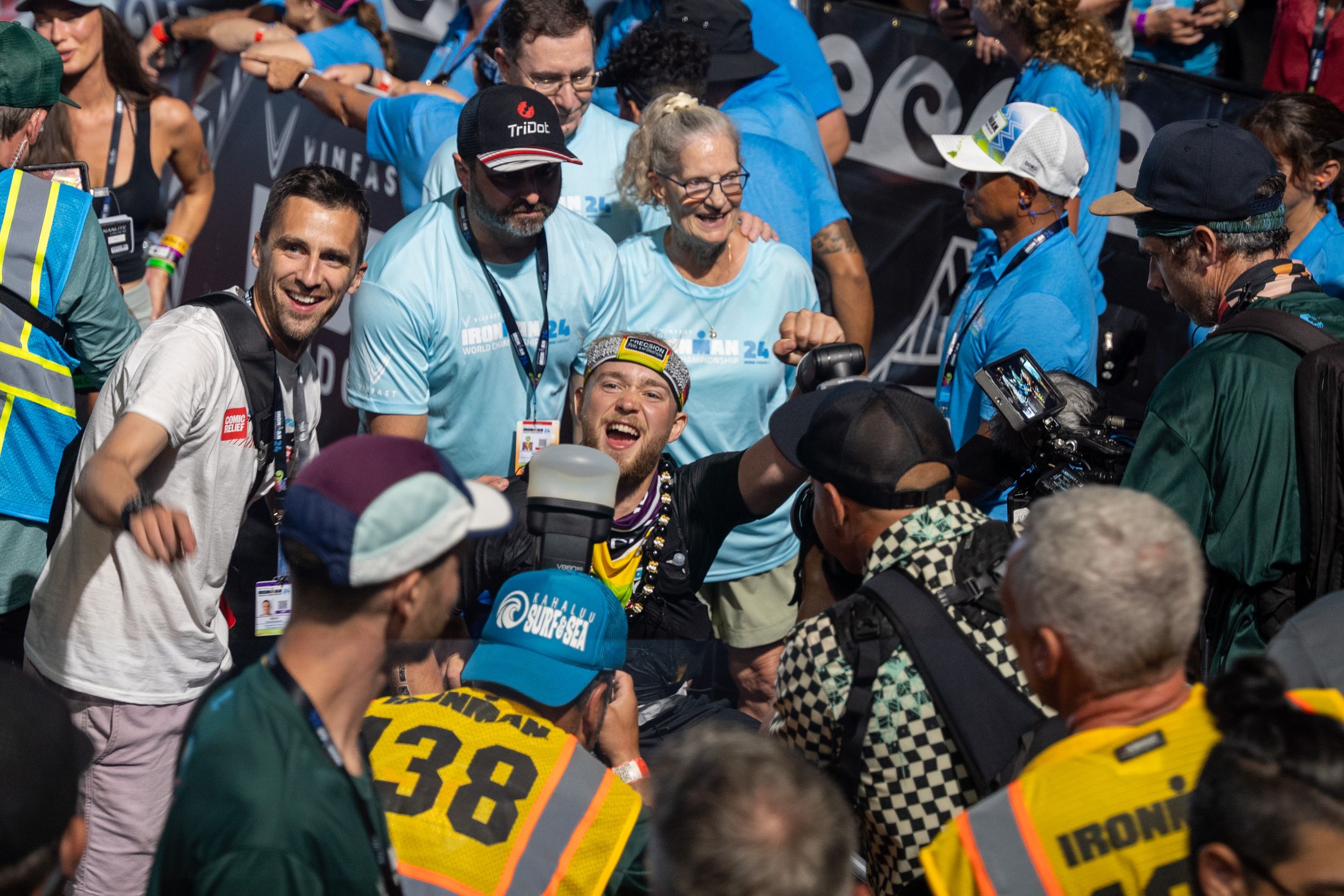 A lively crowd of fans and spectators gather excitedly at a sporting event, with some wearing numbered jerseys.