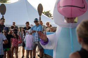 A crowd gathers outdoors around an inflatable character display at a public event.