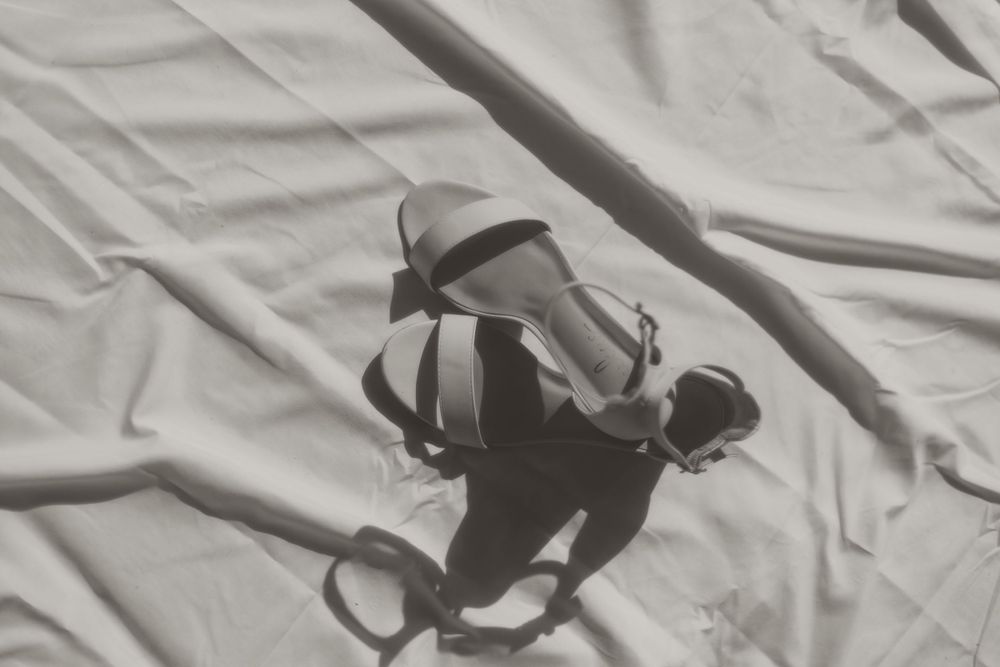 Shadow of ballet dancer with pointe shoes cast on white fabric in dramatic black and white composition.