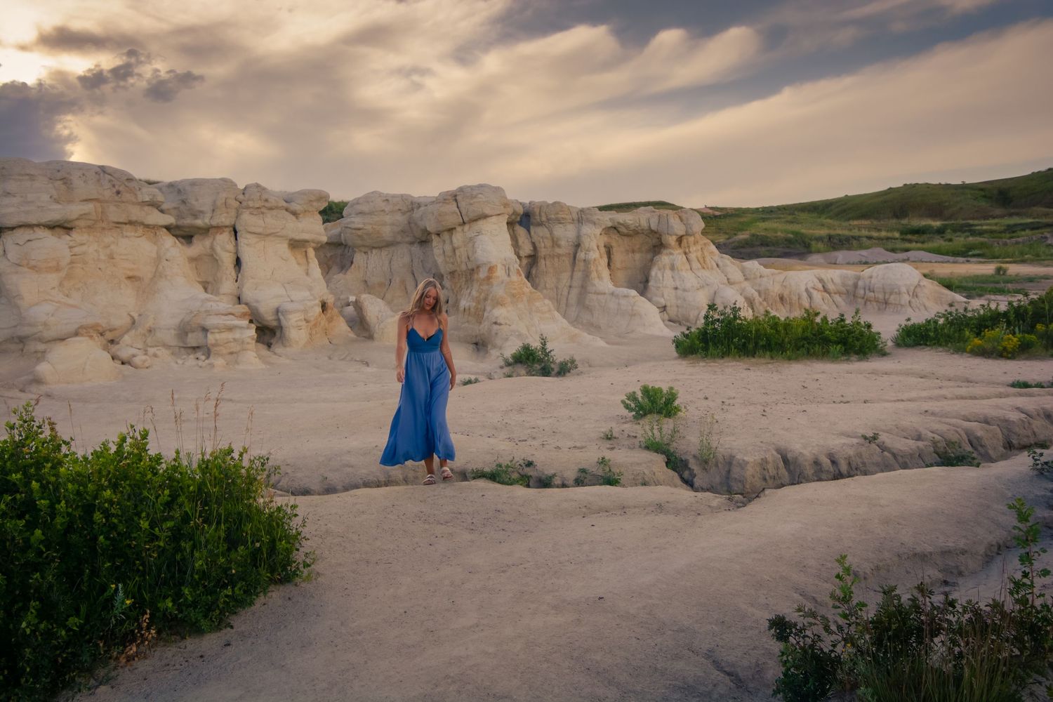 Person in blue dress explores white limestone rock formations at sunset. Paint mines park colorado couples photos