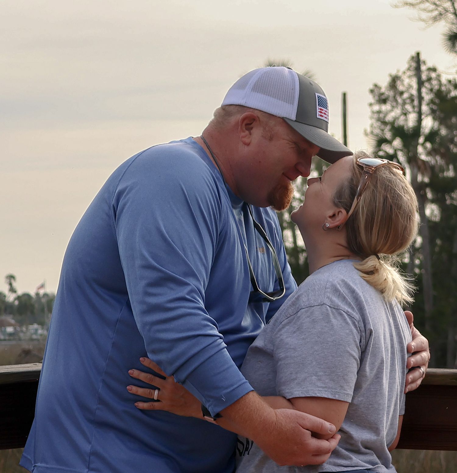 A couple embraces with smiles at sunset.  The joy of their recent photography session still fresh in their minds.