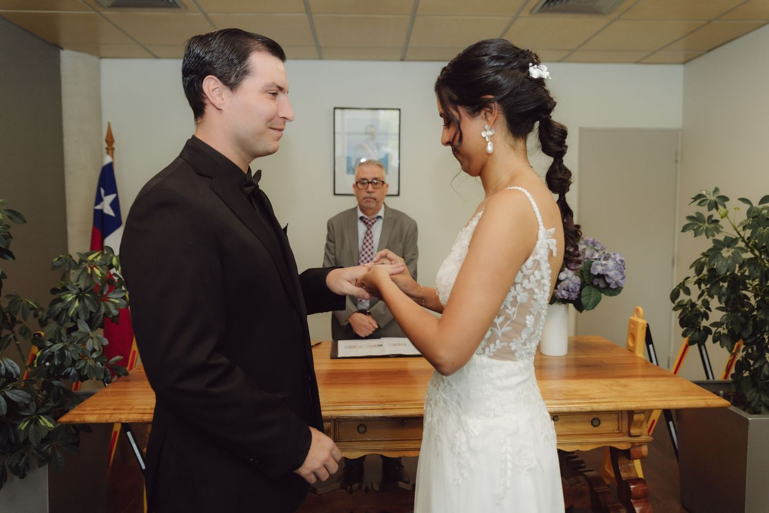 Bride placing wedding ring on groom's finger during intimate civil wedding ceremony.