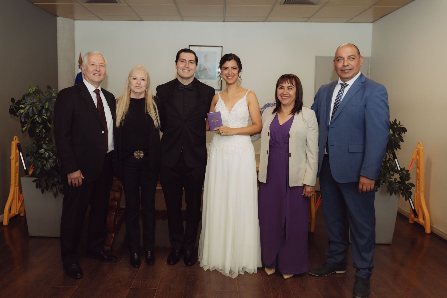 Newlywed couple poses with four family members after civil wedding ceremony in Chile.