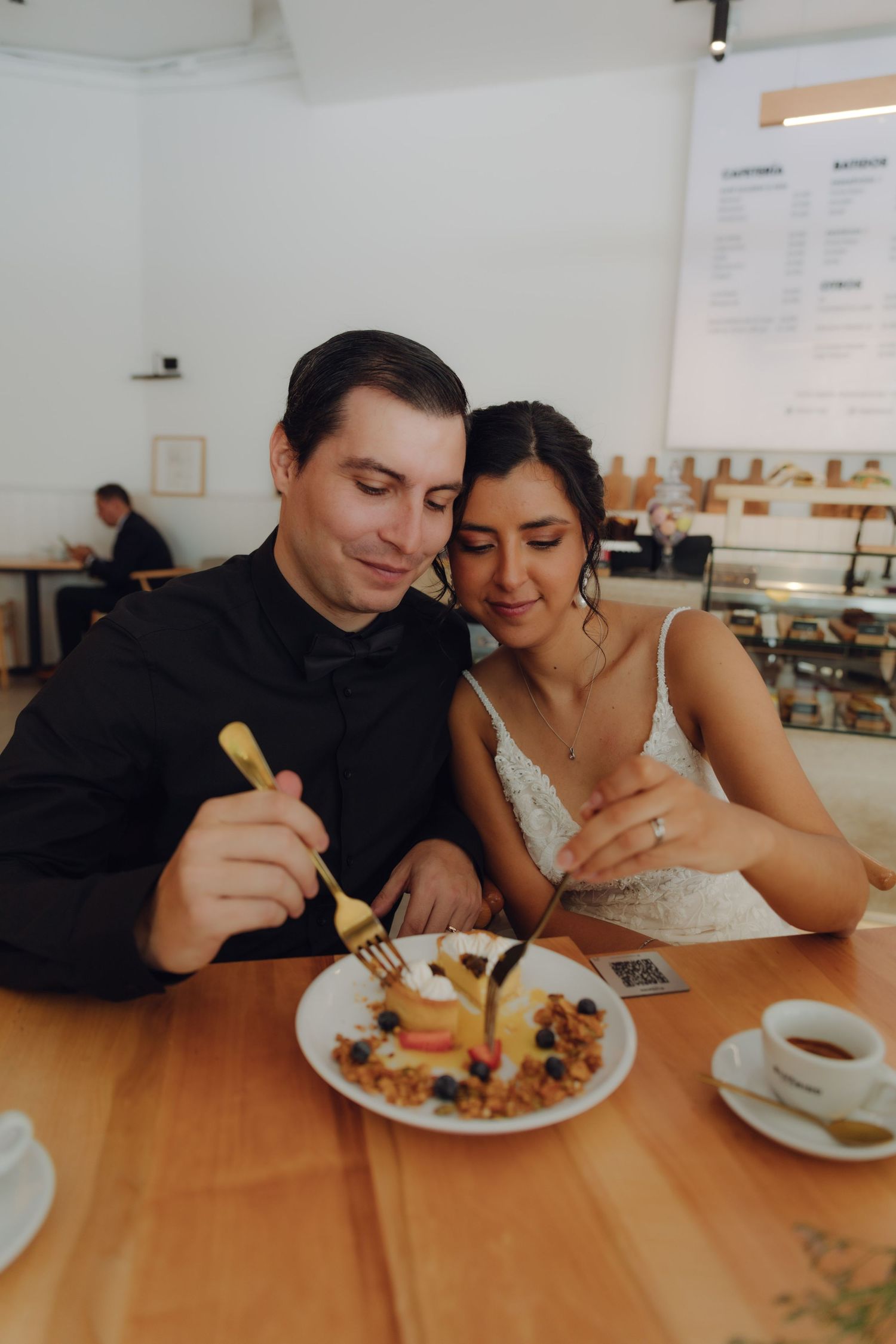 Bride and groom share a dessert together at a cafe on their wedding day.