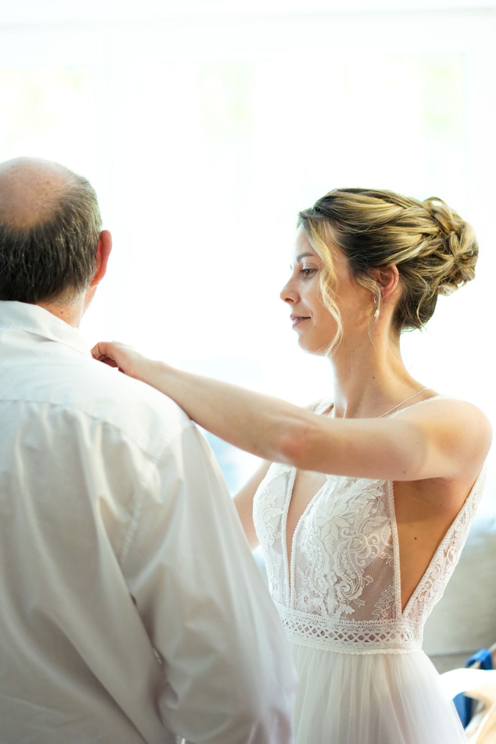 Intimate moment captured in white lace wedding dress with elegant hairstyle.
