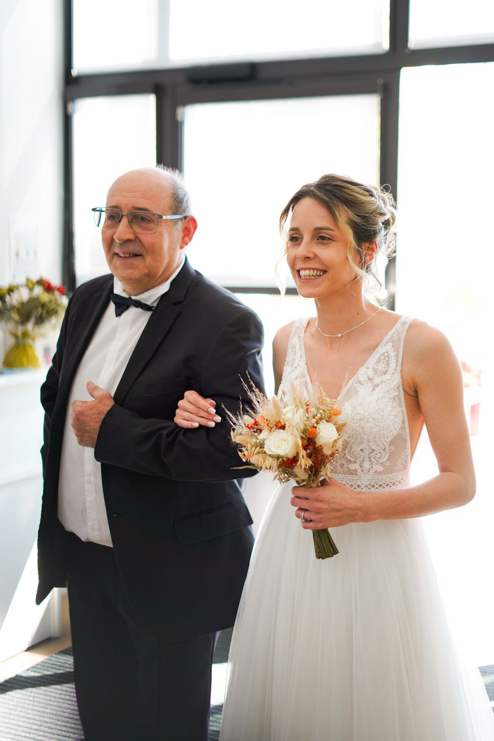 Elegant wedding scene with white lace dress and formal black tuxedo.