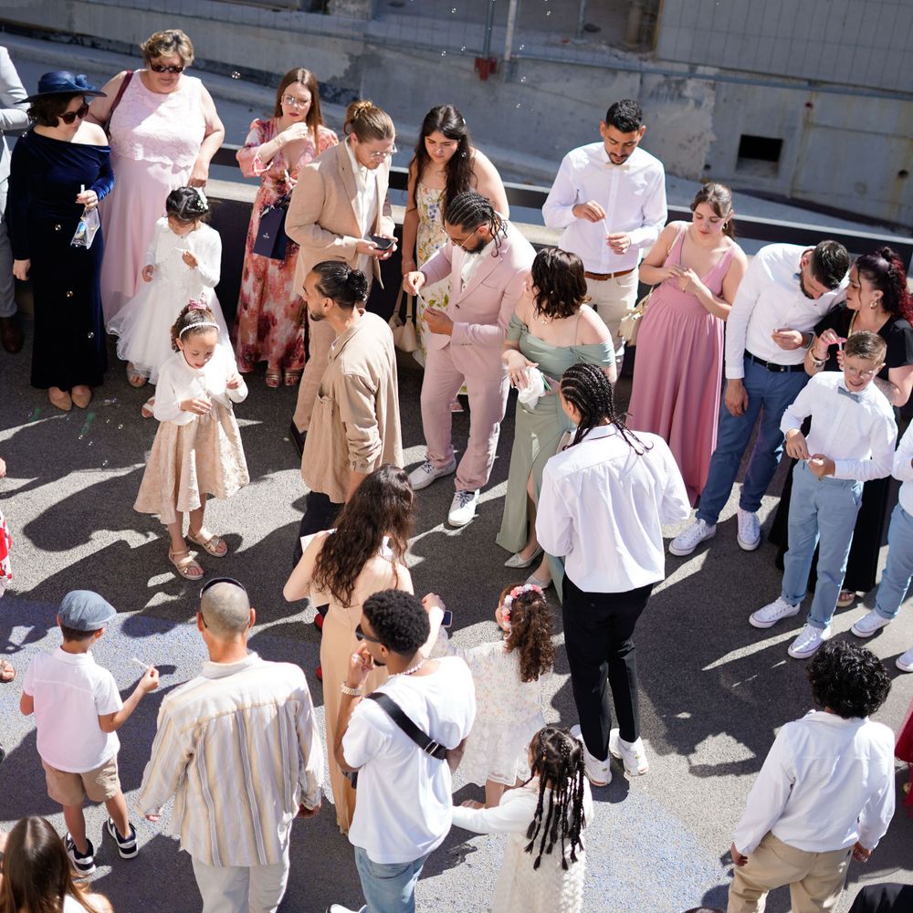Overhead view of wedding guests gathered in casual outdoor celebration wearing light colors.