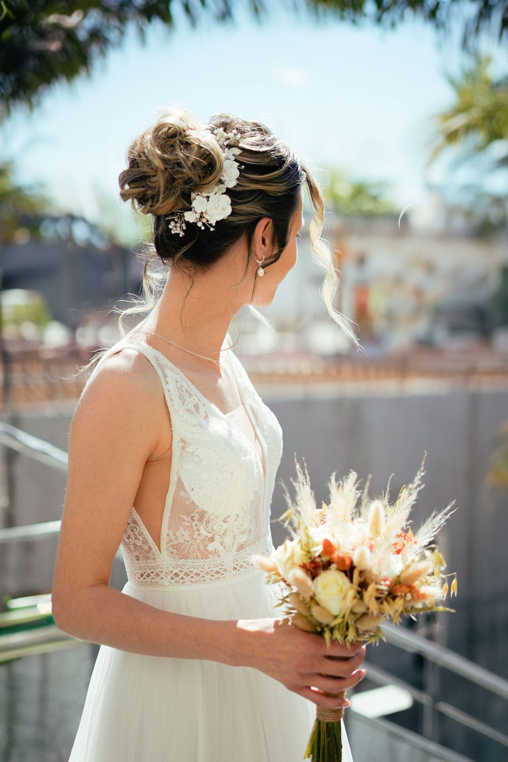 Elegant bridal portrait showing lace dress details and romantic updo hairstyle with floral accessories.