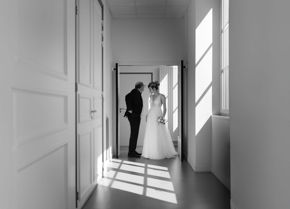 Black and white image of a couple silhouetted in a sunlit hallway.