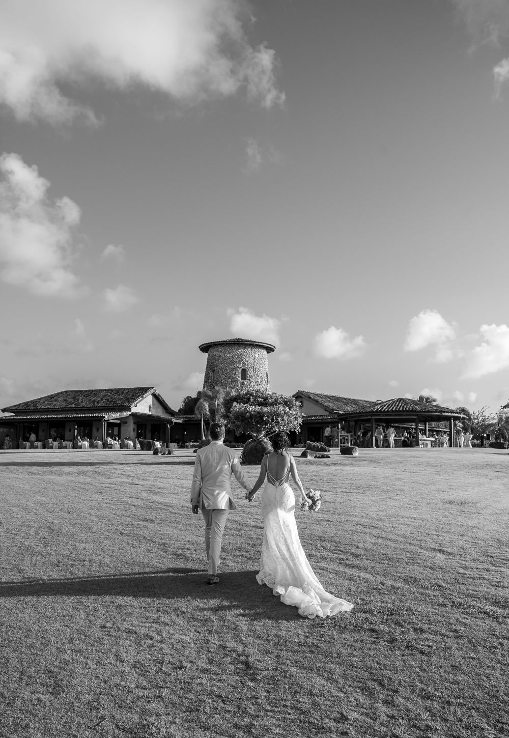 Black and white wedding portrait featuring a historic Mediterranean venue with stone tower.