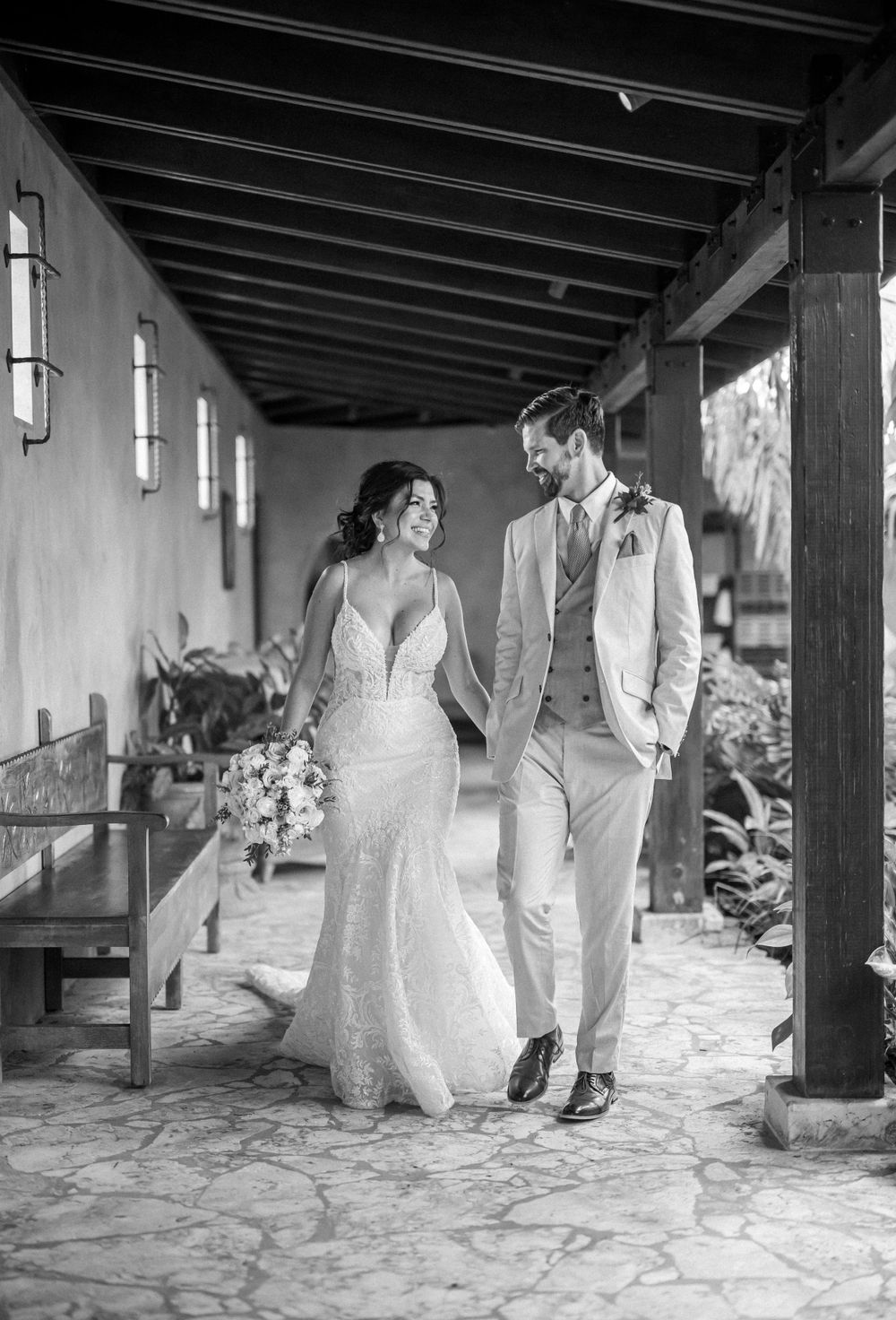 Black and white portrait in a covered walkway with exposed beam ceiling and stone floor.