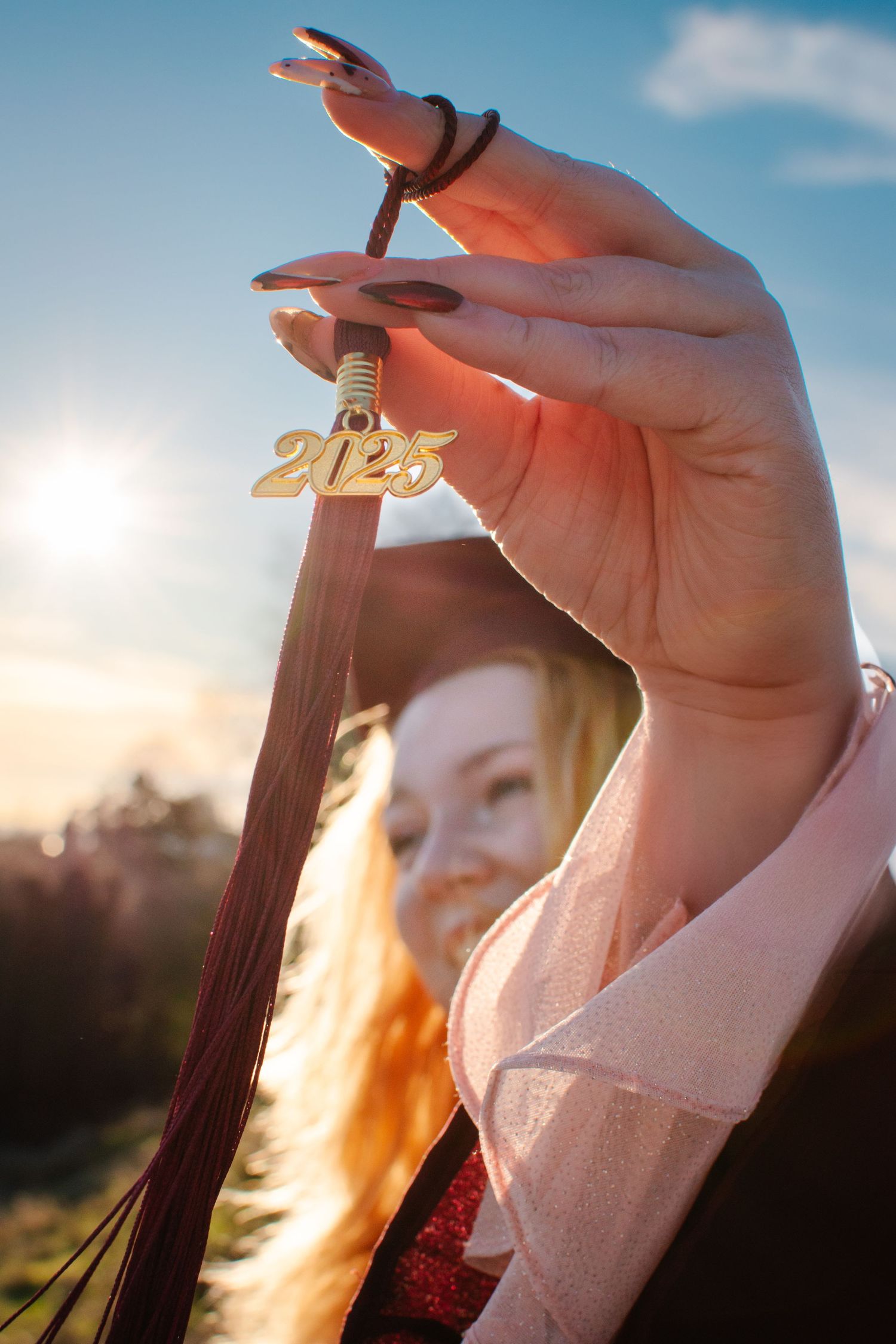 Close-up of senior graduate holding 2025 tassel in the sunlight, creative graduation photo idea in Seattle.