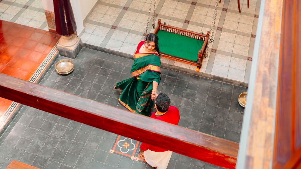 High angle view of a person in green and red clothing sitting on a tiled floor during a creative activity.