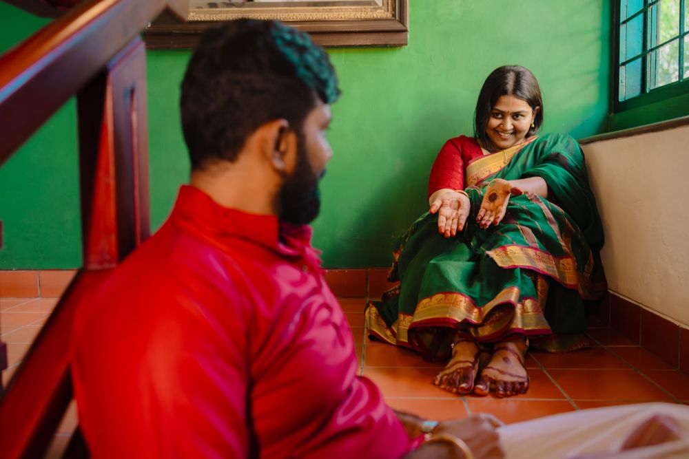 People in traditional Indian attire share a candid moment together on a wooden floor against a green wall.