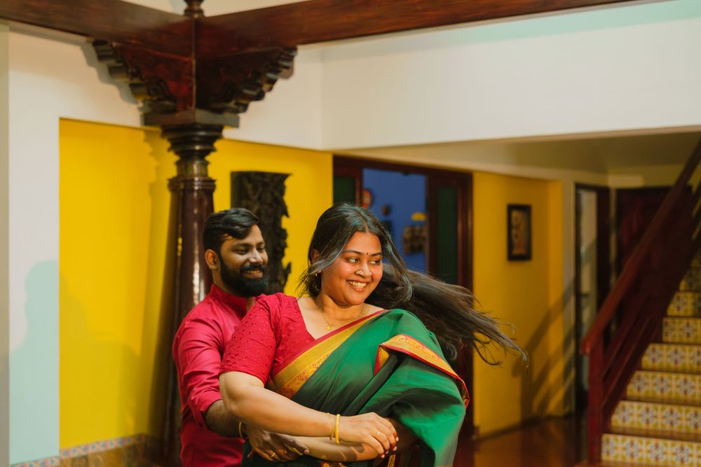 Two people share a warm embrace in a corridor with yellow walls and wood accents.