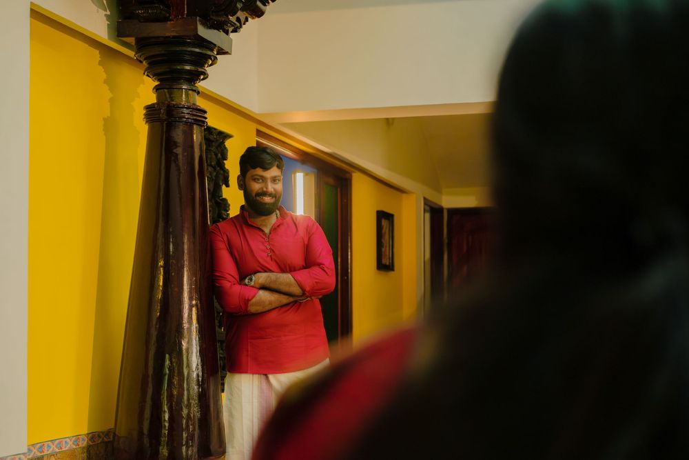 A person in a red shirt stands in a yellow hallway next to a decorative wooden pillar.
