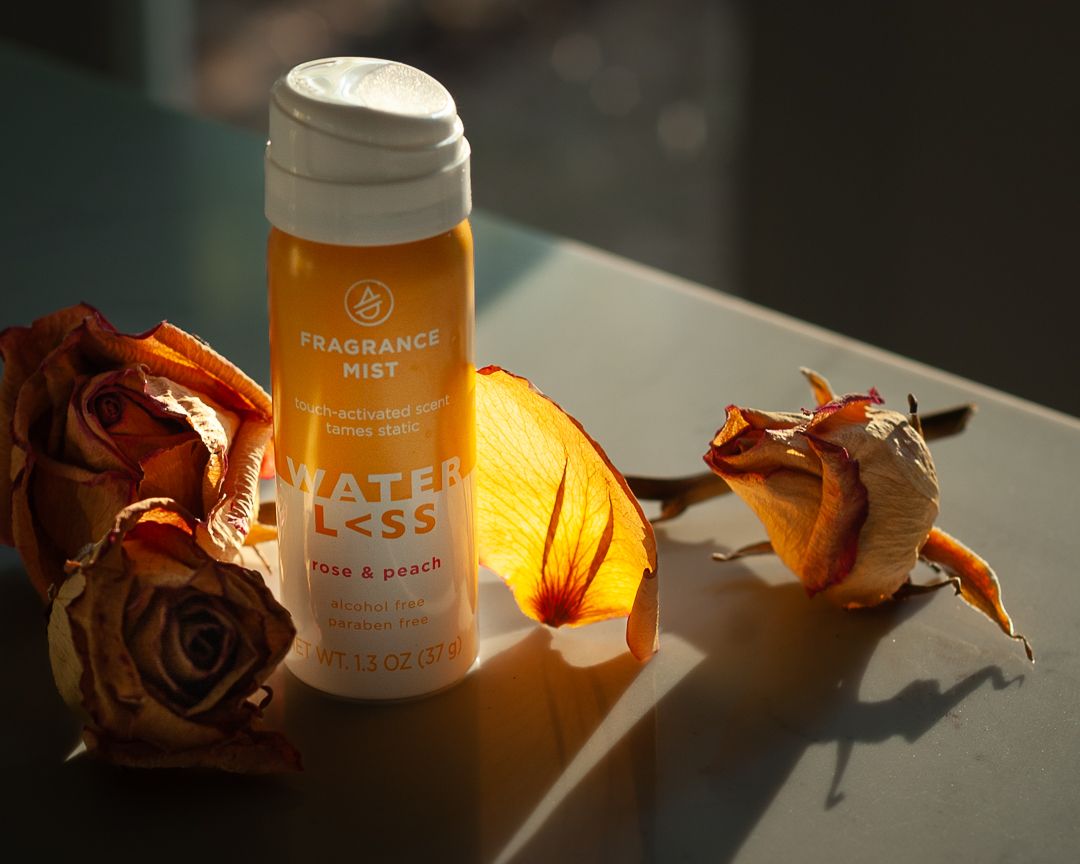 Orange fragrance bottle with dried roses photographed in warm sunlight. Product photography, San Diego, California