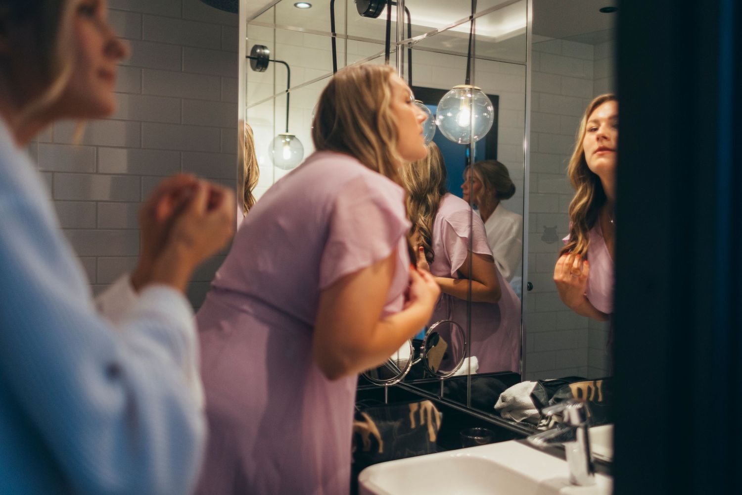Wedding party getting ready in a modern hotel bathroom with bright lighting.