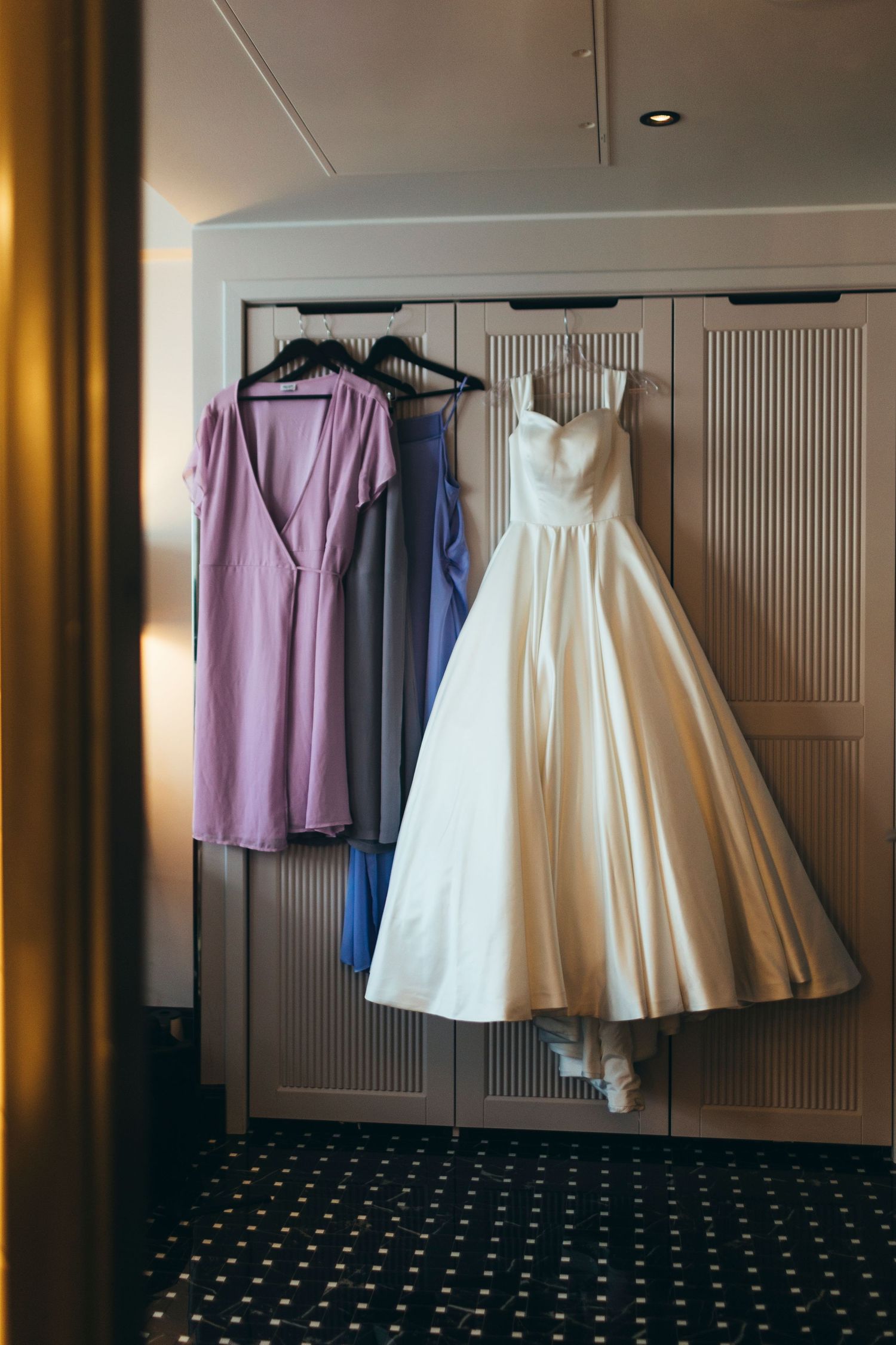 Wedding dresses and bridesmaid gowns hanging on a closet rack.