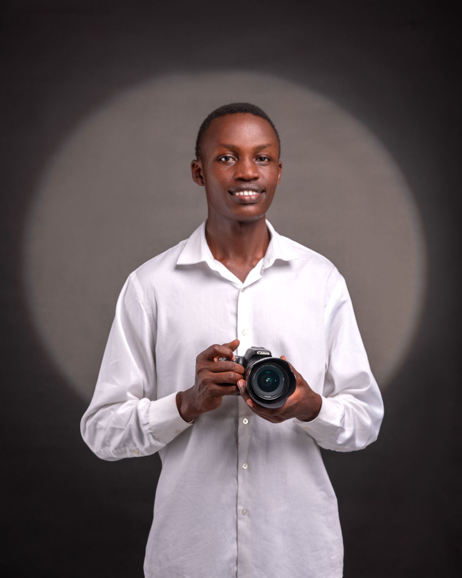 A man with camera poses behind is circular shape on a backdrop