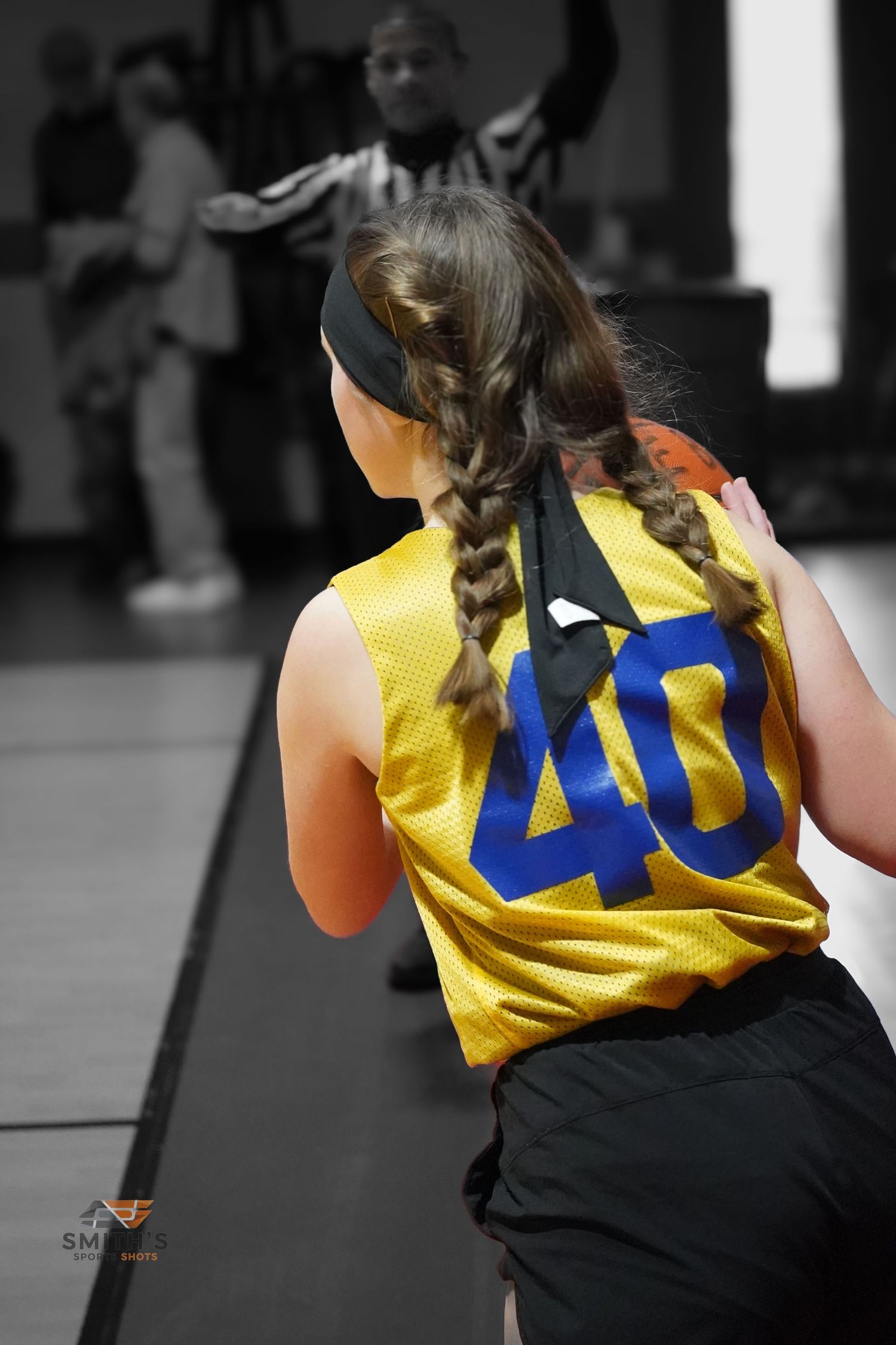 Basketball player wearing yellow jersey number 40 with braided hair seen from behind during game or practice.
