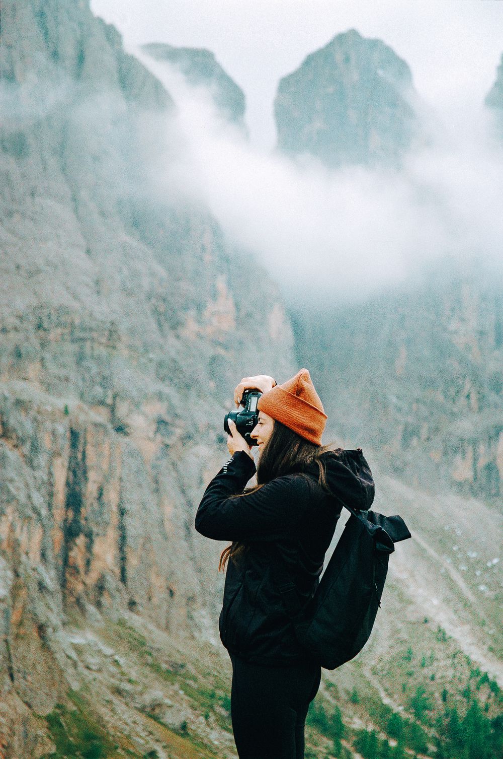 Photographer capturing misty cliffs in dramatic alpine setting