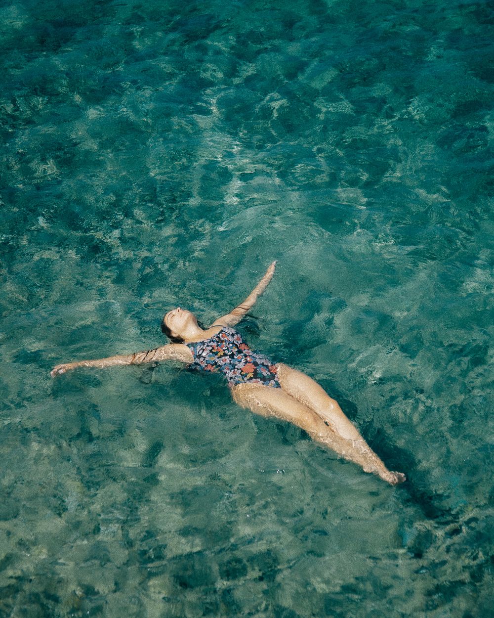 Woman floating serenely in crystal-clear turquoise sea