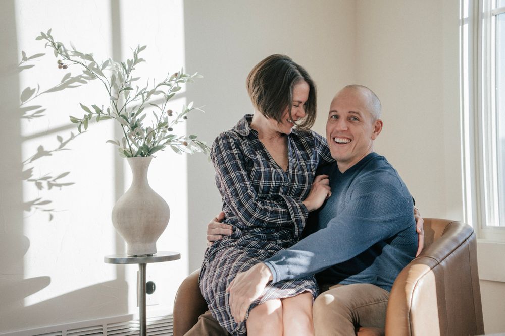 A couple shares a joyful moment while sitting together in a sunny indoor setting.