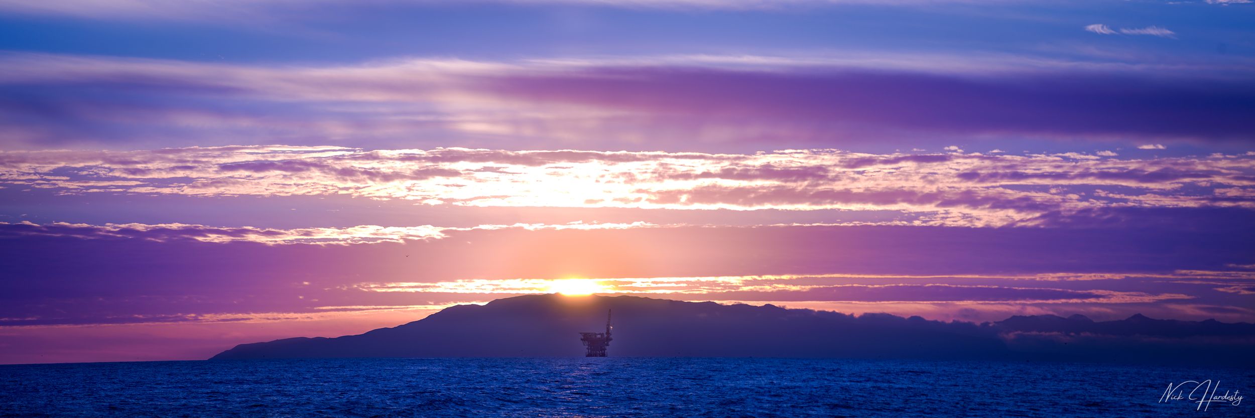 Panoramic view of Santa Cruz coastline at sunset, with purple-tinted skies blending into the ocean horizon