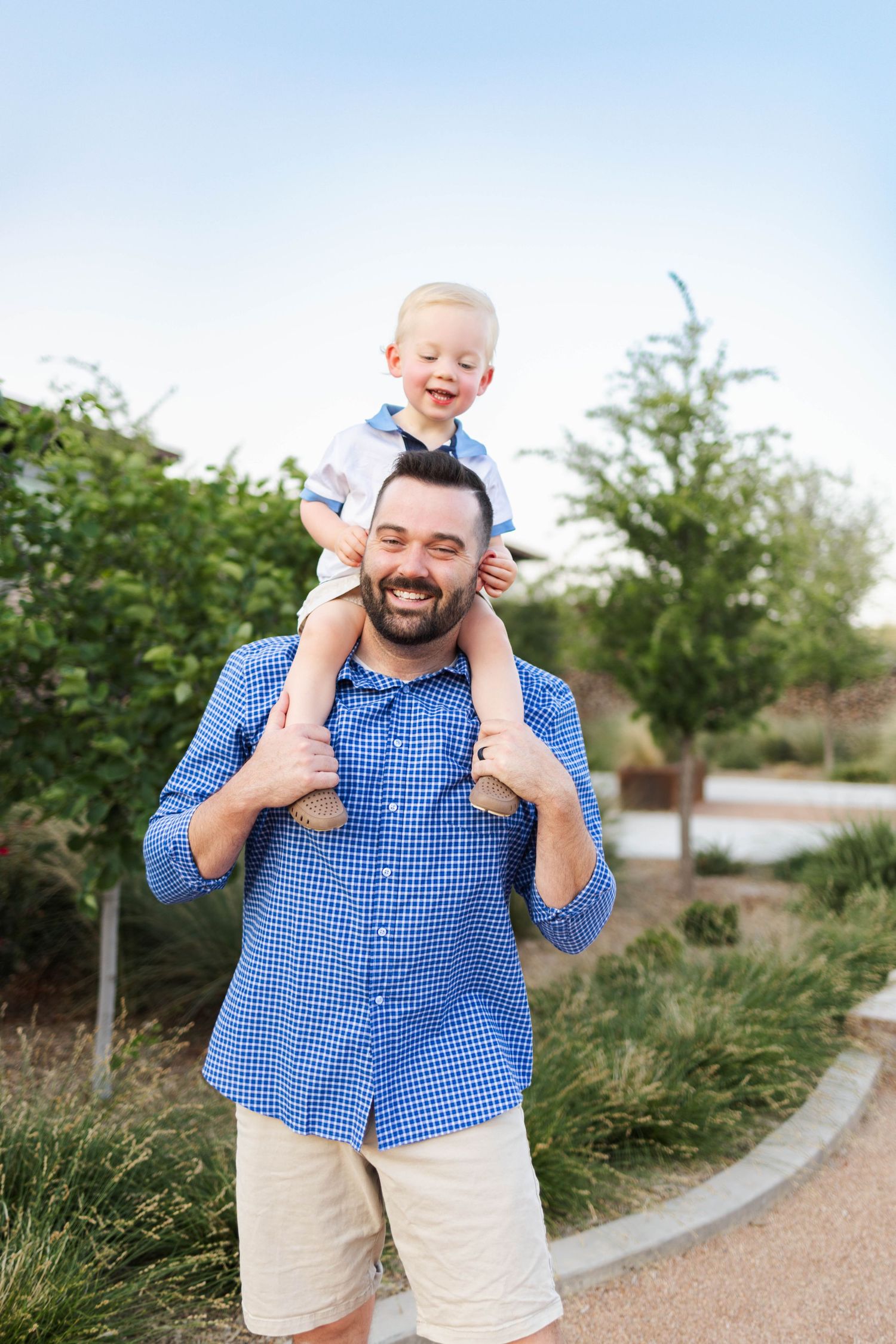 A parent and child enjoy a playful moment outdoors on a path surrounded by greenery.