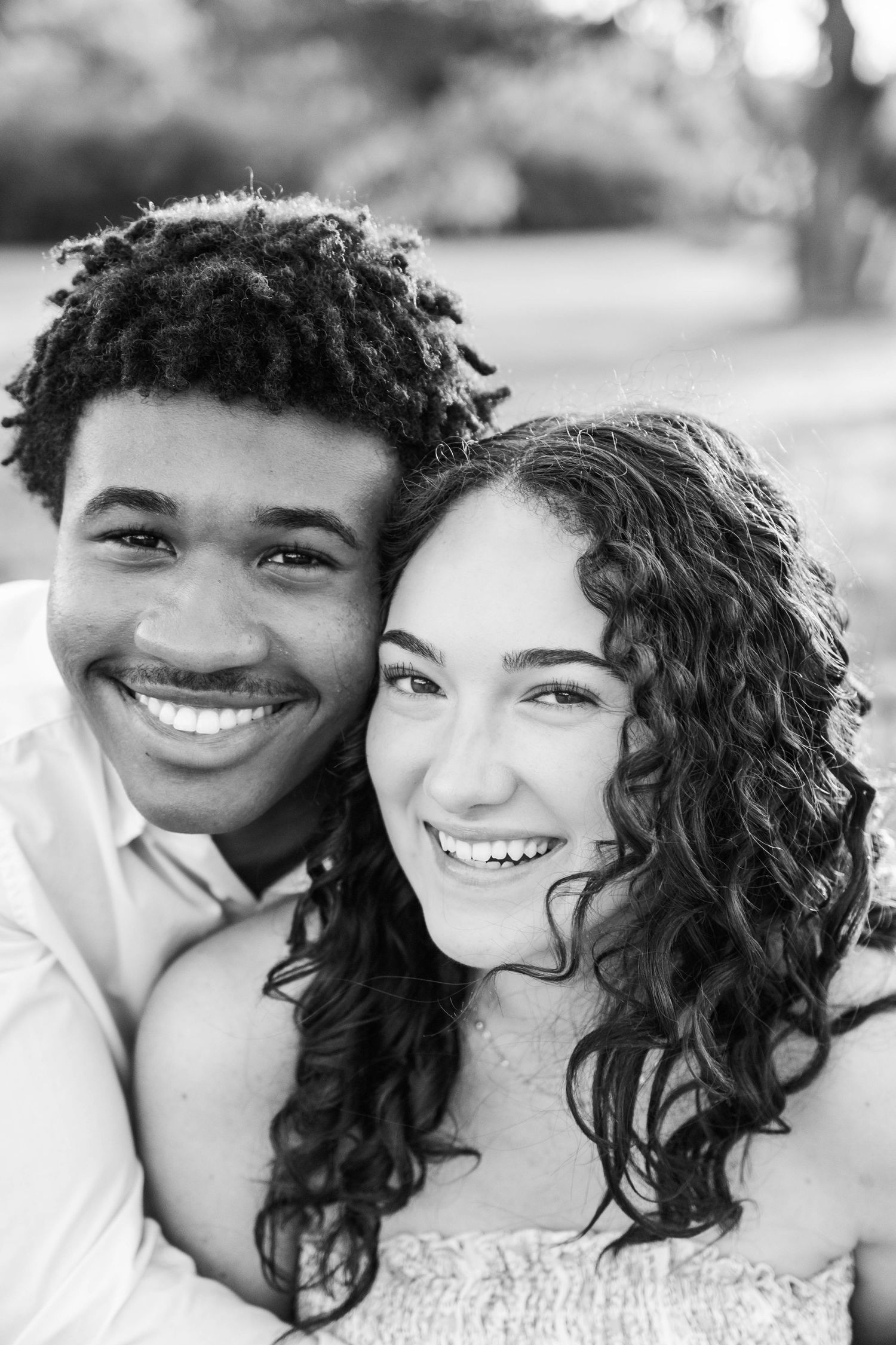 Black and white portrait of a joyful young couple smiling together in a tender embrace.