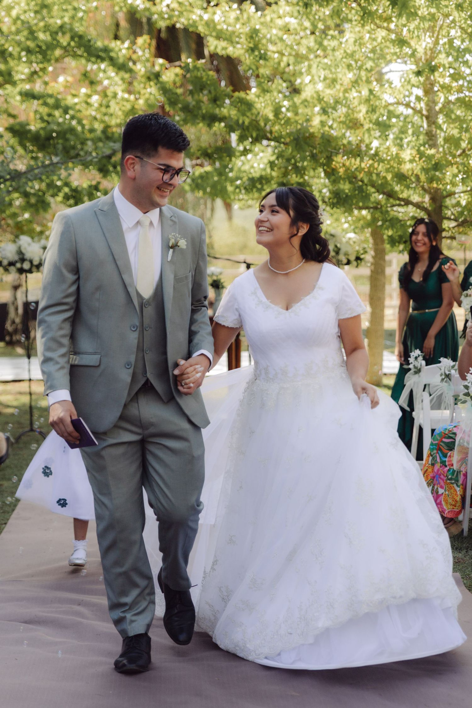 Happy bride and groom walk together smiling after their outdoor garden wedding ceremony.