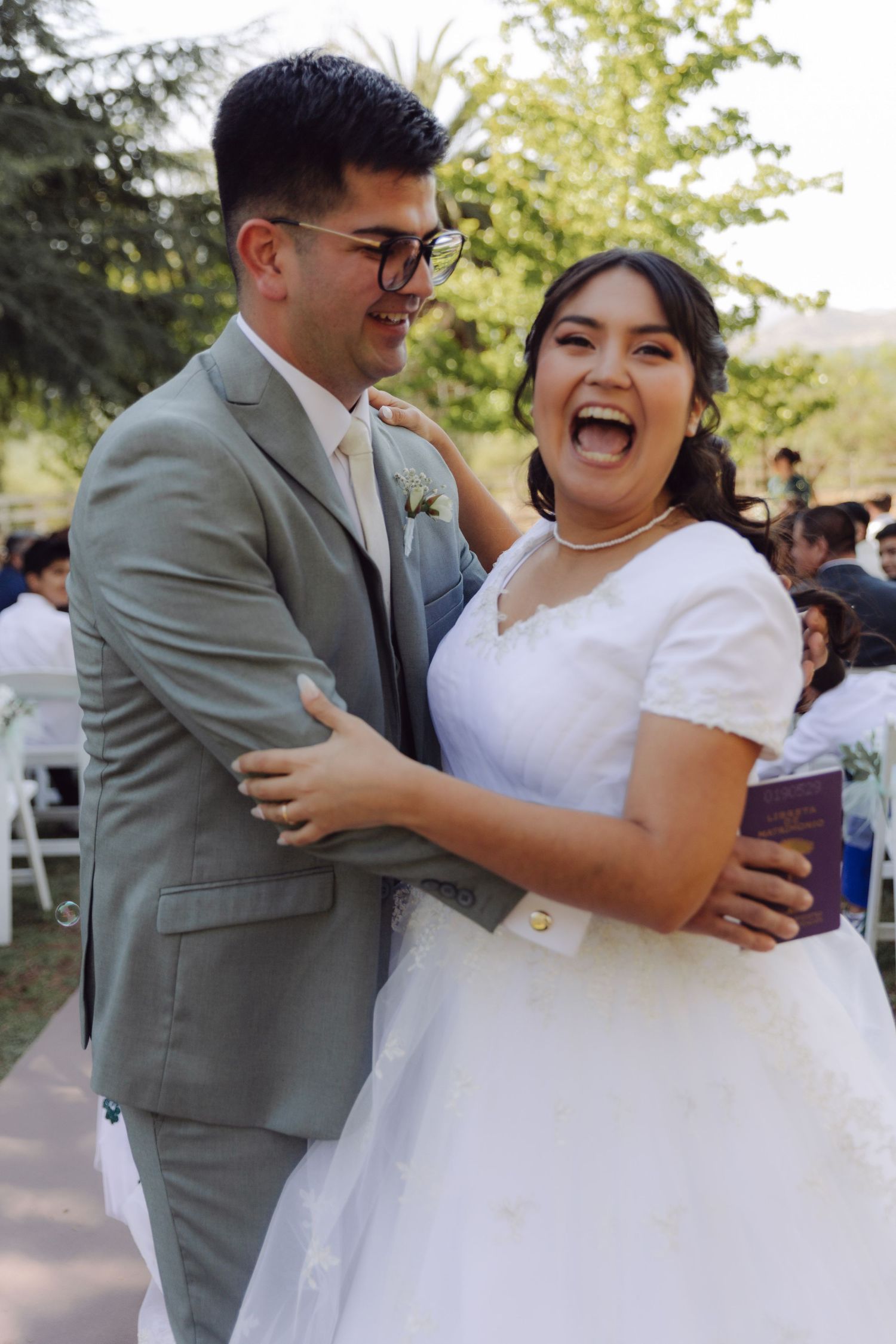 Joyful bride laughs and embraces groom after outdoor wedding ceremony conclusion.