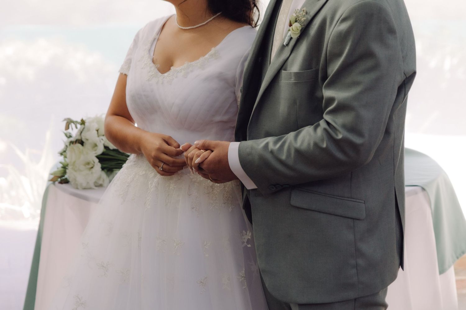 Bride and groom stand together holding hands during outdoor wedding ceremony.
