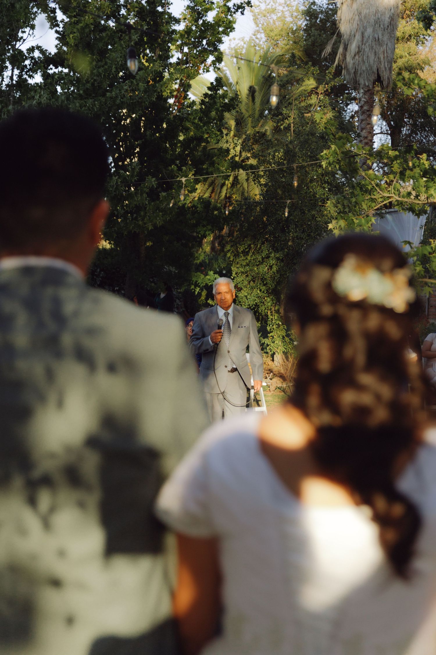 Guest delivers a heartfelt speech to the bride and groom at an outdoor wedding ceremony.