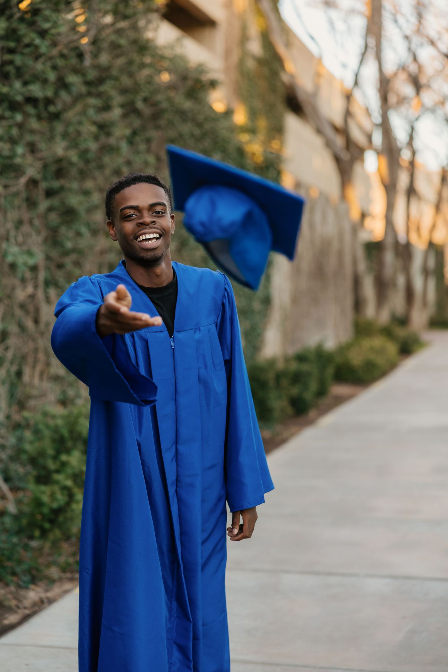 Senior posing in downtown Amarillo, Texas in front of colorful mural in his cap and gown for his high school graduation photoshoot.